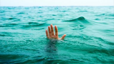 Photograph of a hand reaching out through the waves of the sea